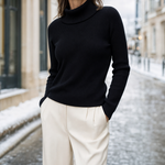 Harlow Roll Neck Sweater in black worn with cream trousers, front view